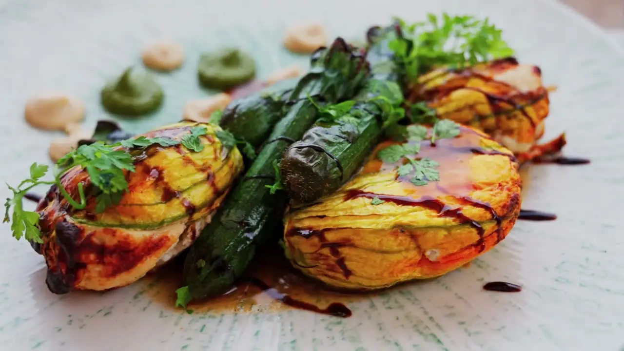 A plated course of grilled peaches and charred asparagus finished with balsamic
